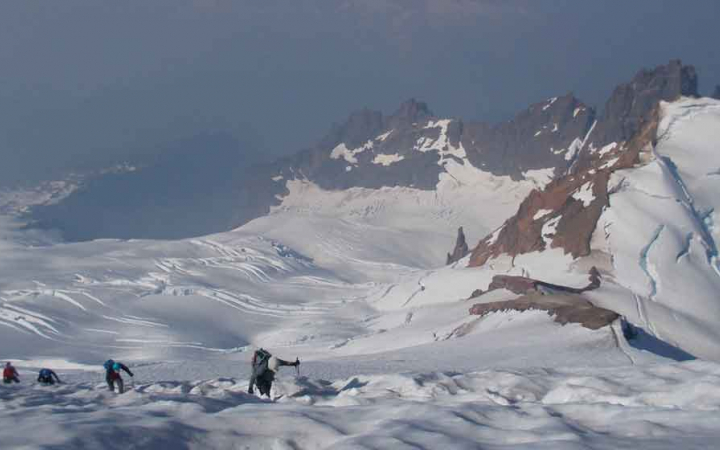 four students navigate a snowy mountainous landscape
